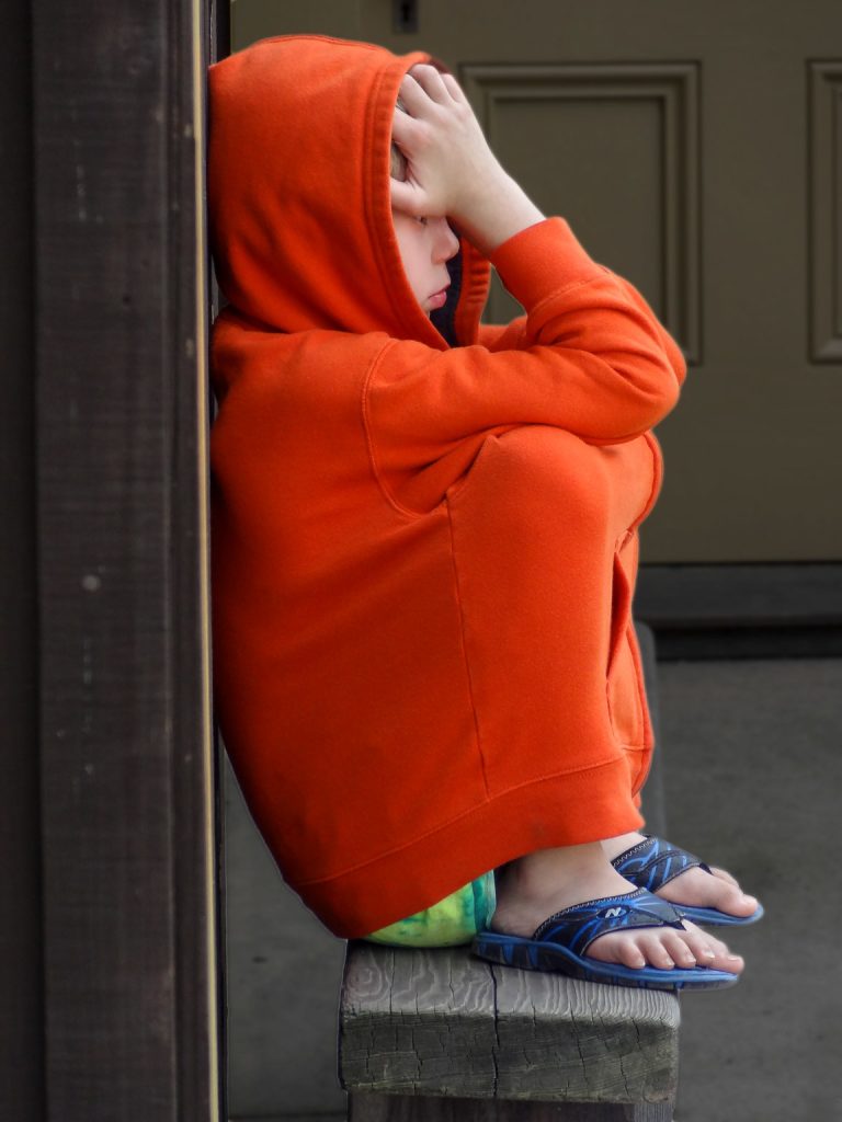 A young boy sits outside a museum after a disagreement with his mother