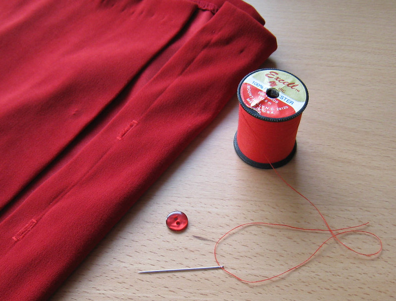 Red spool of thread and needle