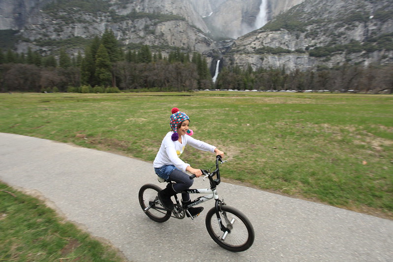Girl rides bike past Yosemite Falls