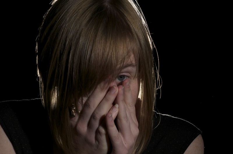 Person in the dark with hands covering their face