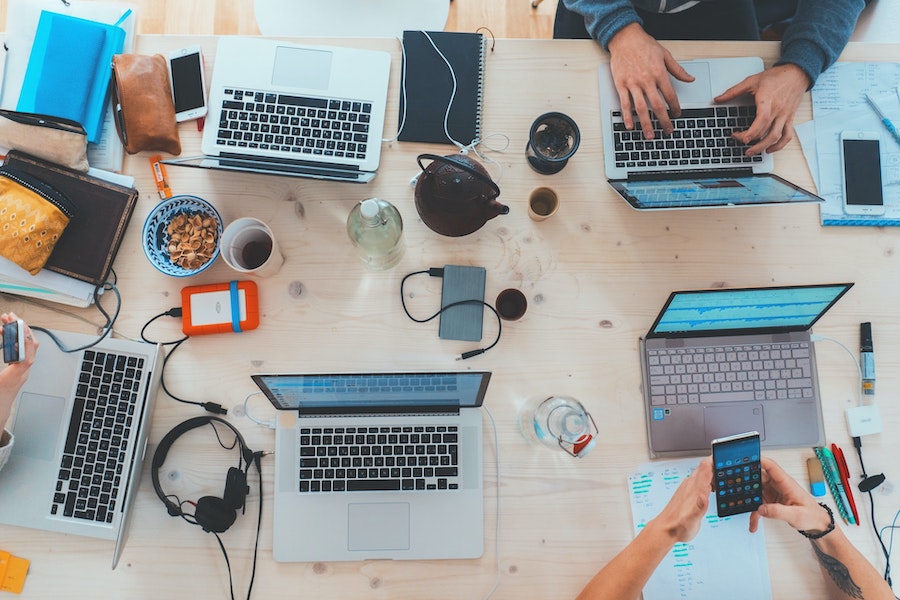 People working at a table on laptops and cellphones